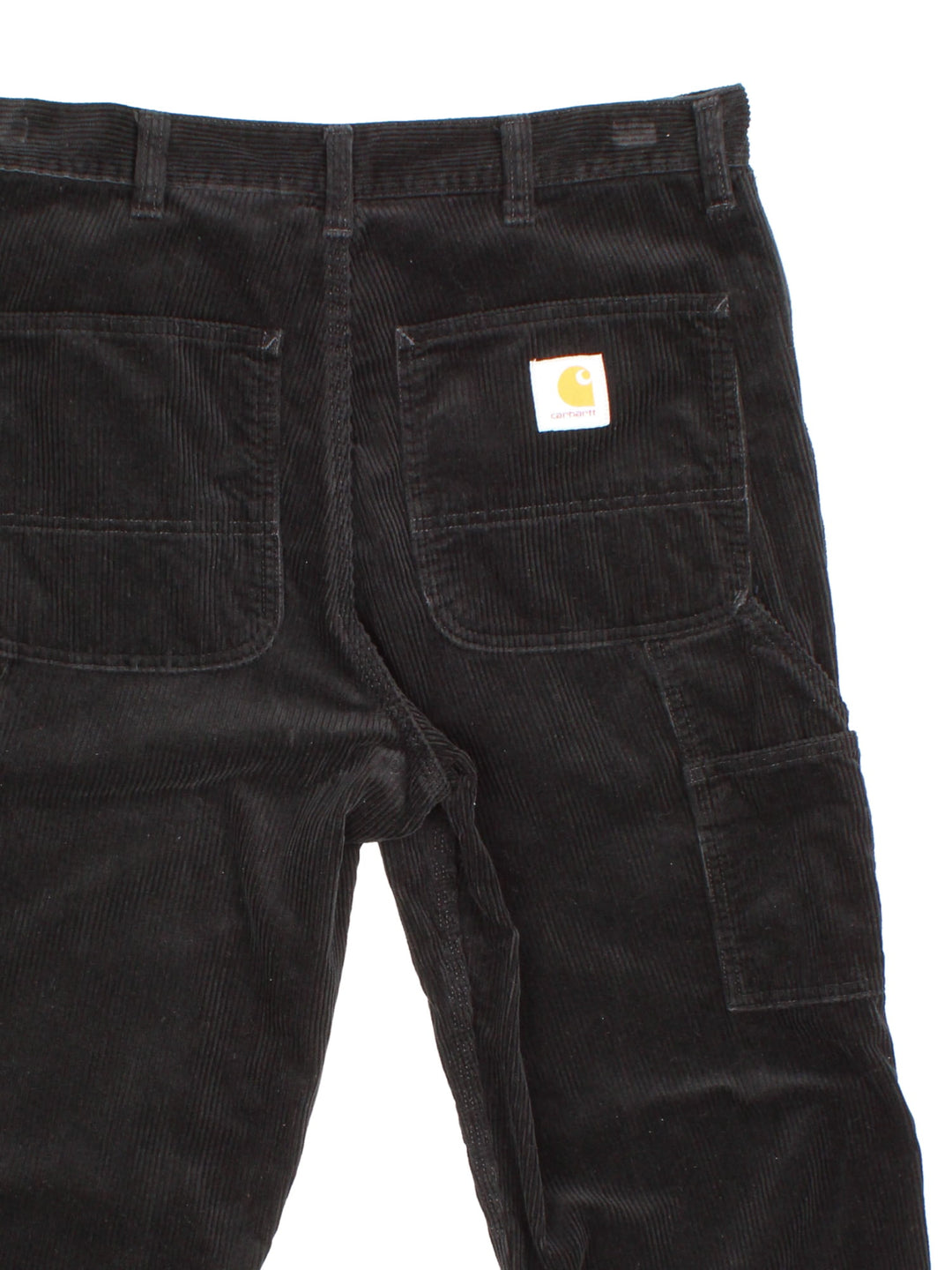 Carhartt corduroy trousers in black with multiple pockets, a hammer loop, zip and button closure, and a logo patch on the back pocket.