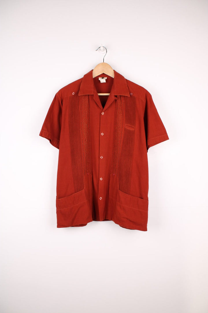 Burnt orange embroidered short-sleeved shirt with three pockets. 