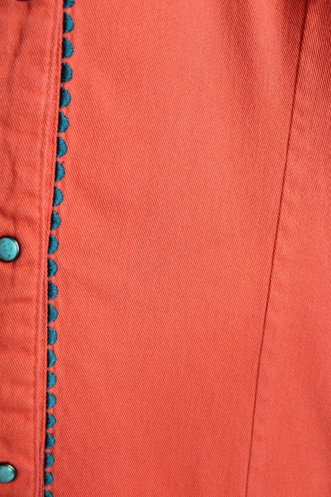 Pink Wrangler western shirt with floral embroidery on yoke, pockets and cuffs, a ram's skull embroidered on the back, and turqoise-effect snap closure. 