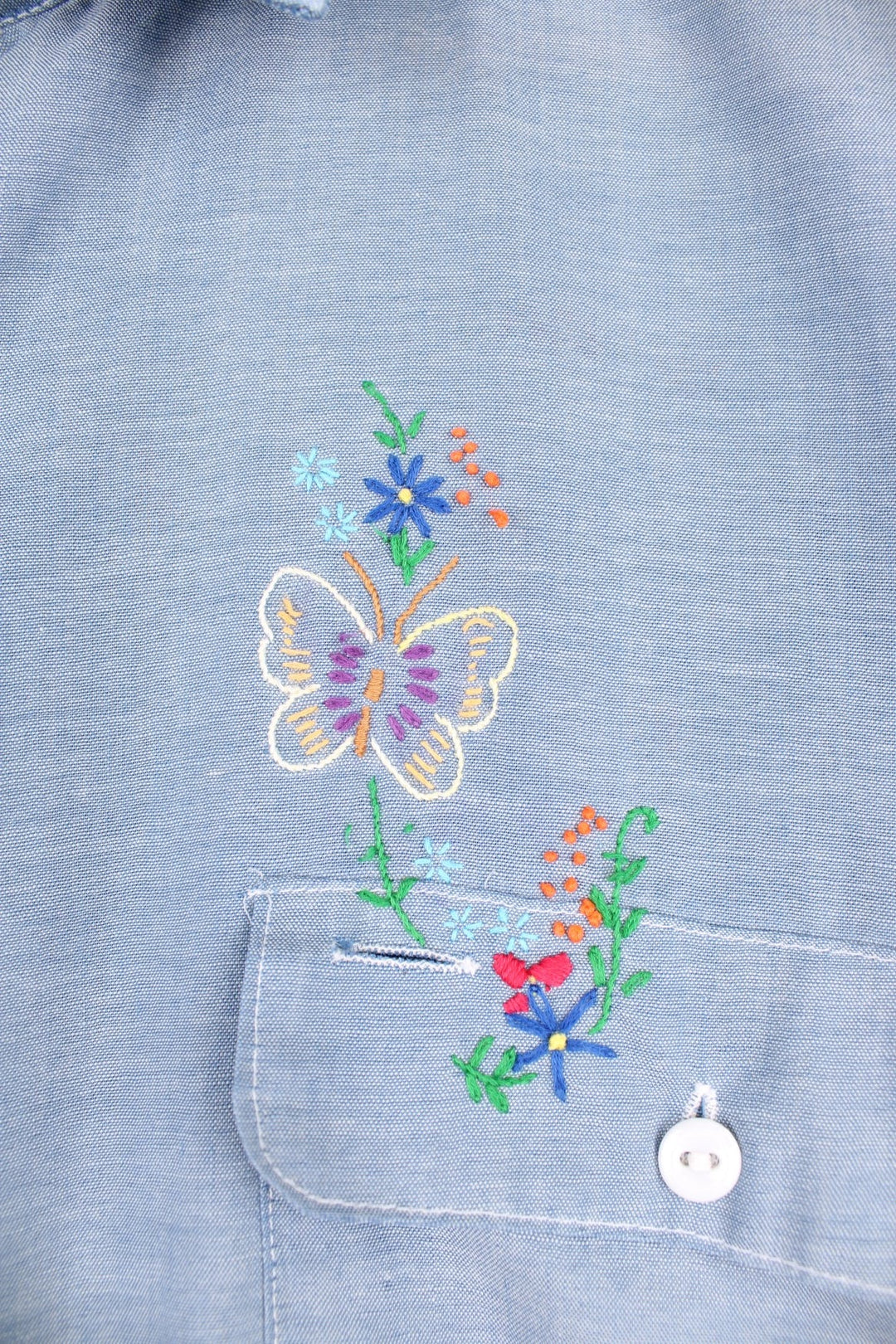 Grey western shirt with colourful embroidery on the front and back, with two flap pockets. 