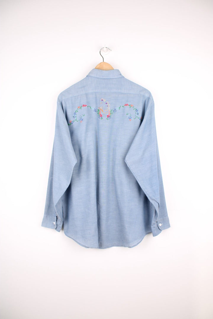 Grey western shirt with colourful embroidery on the front and back, with two flap pockets. 