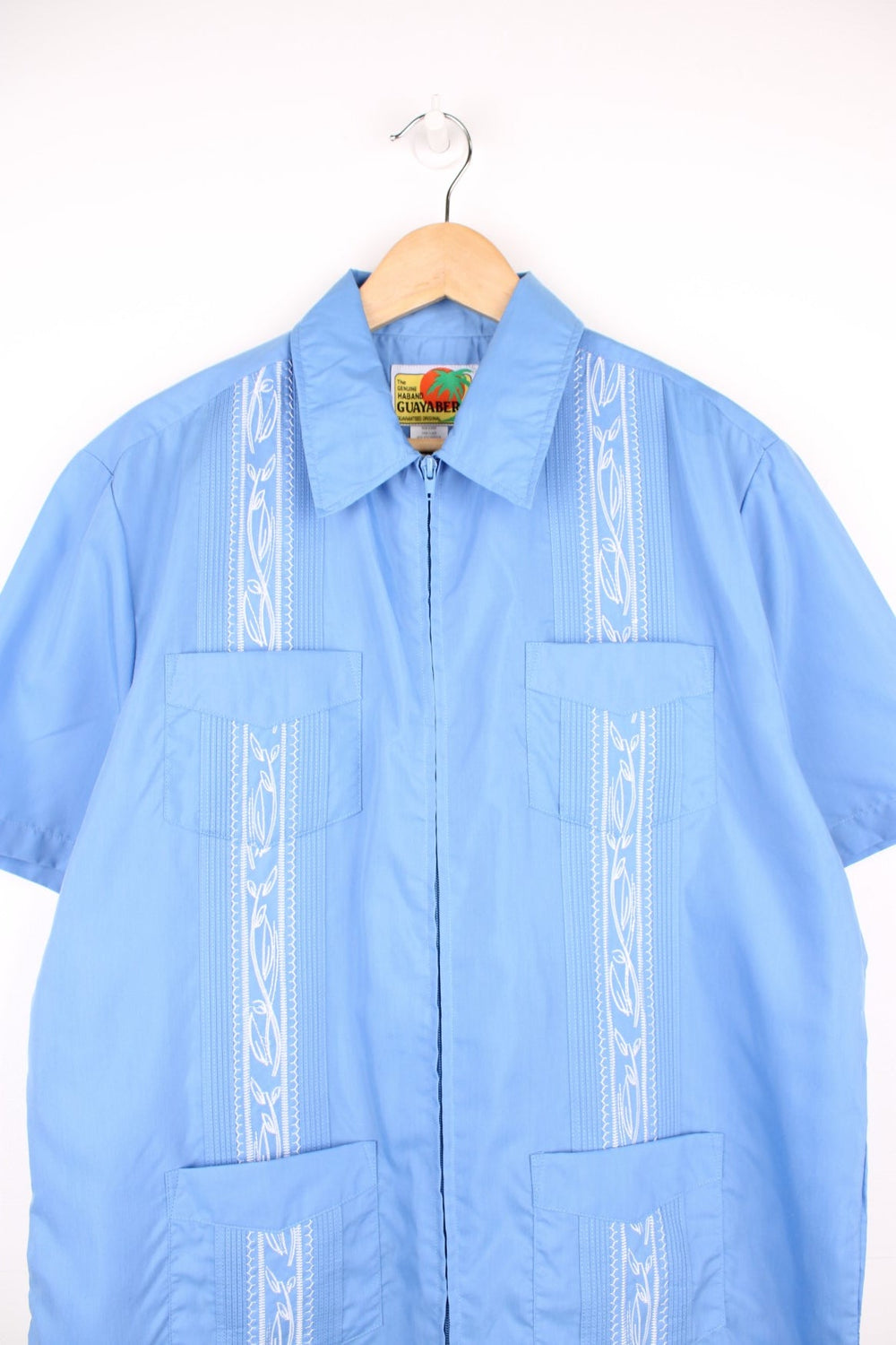 Blue short-sleeved embroidered Cuban shirt with four pockets and zip closure. 