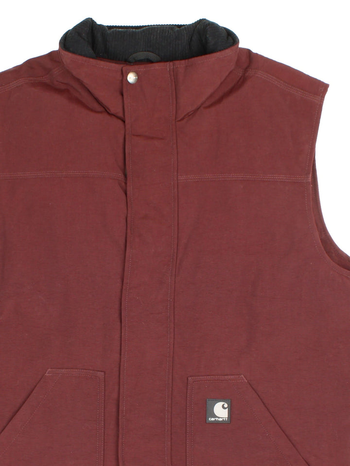 Carhartt Gilet in a burgundy red colourway. Zips up and has side pockets, insulated with a quilted lining, and has the logo embroidered on the front.