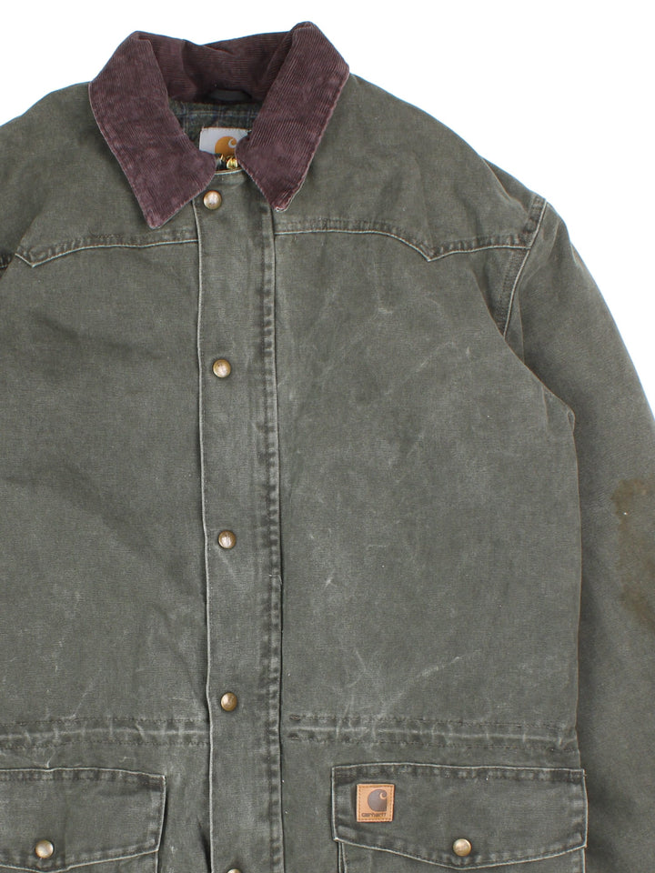 Vintage Carhartt Barn Chore Jacket in a green colourway. Buttons up and has double pockets on the front, brown corduroy collar, blanket lining, and has the logo embroidered on the front.