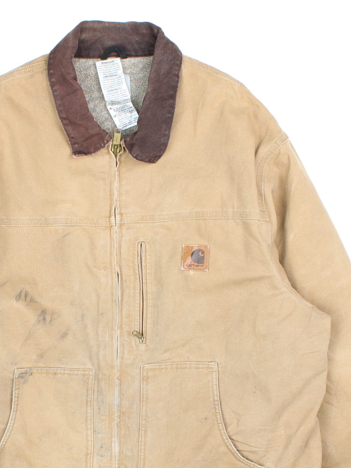 Vintage Carhartt Arctic Jacket in a tan colourway. Zips up and has multiple pockets, insulated with a sherpa lining, has the logo embroidered on the front, and 'Flora Trucking Inc' company logo / spell out embroidered on the back.