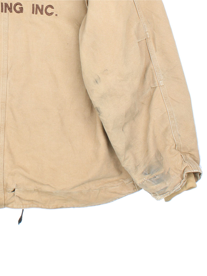 Vintage Carhartt Arctic Jacket in a tan colourway. Zips up and has multiple pockets, insulated with a sherpa lining, has the logo embroidered on the front, and 'Flora Trucking Inc' company logo / spell out embroidered on the back.