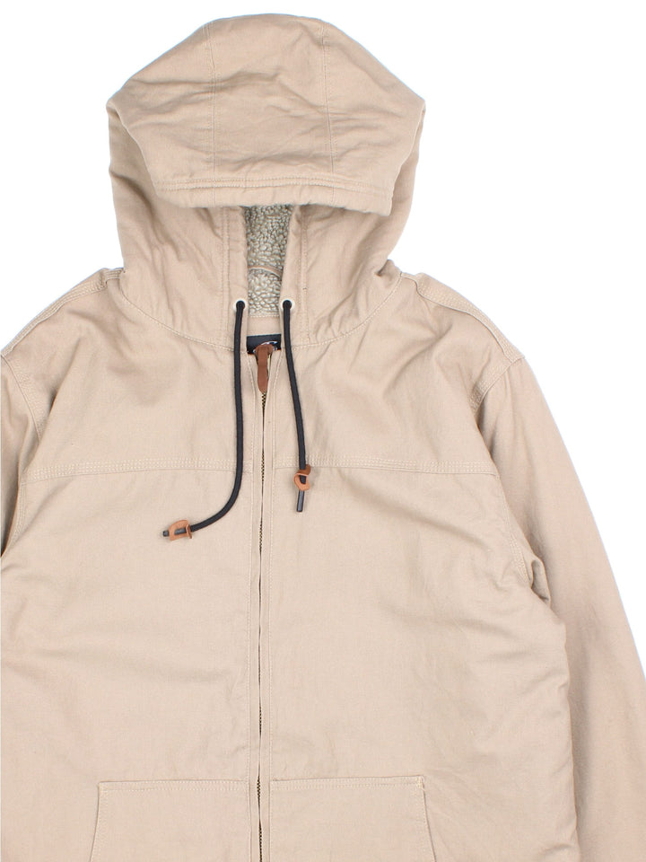 Vintage O'neill Canvas Parka Jacket in a tan colourway. Zips up and has side pockets, insulated with a sherpa lining, hooded, 0and has the logo tab embroidered on the back.