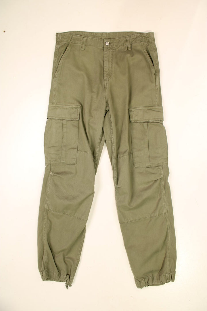 Carhartt Cargo Trousers in a green colourway with multiple pockets and the logo embroidered on the back.