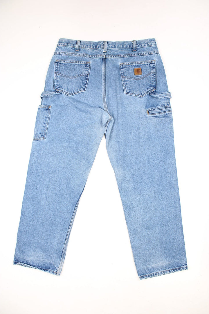 Carhartt light wash carpenter jeans with front, back and side pockets. two hammer loops, and a logo patch on the back pocket. 