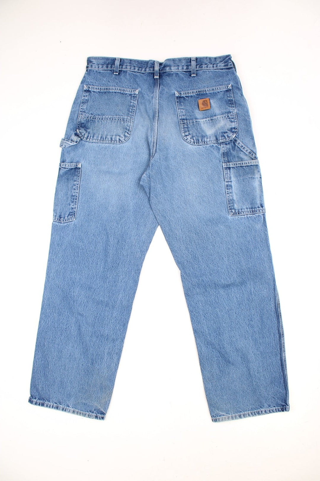 Carhartt light wash carpenter jeans with front, back and side pockets, a hammer loop, and a logo patch on the back pocket. 