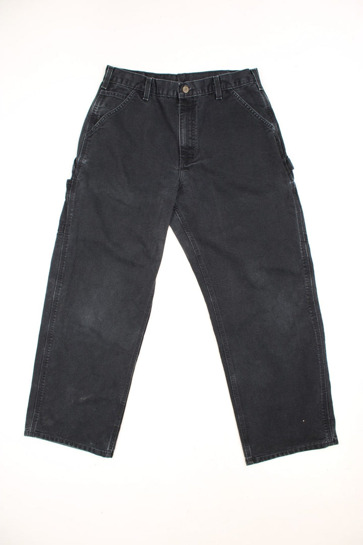 Carhartt black carpenter jeans with front, back and side pockets, a hammer loop, and a logo patch on the back pocket. 