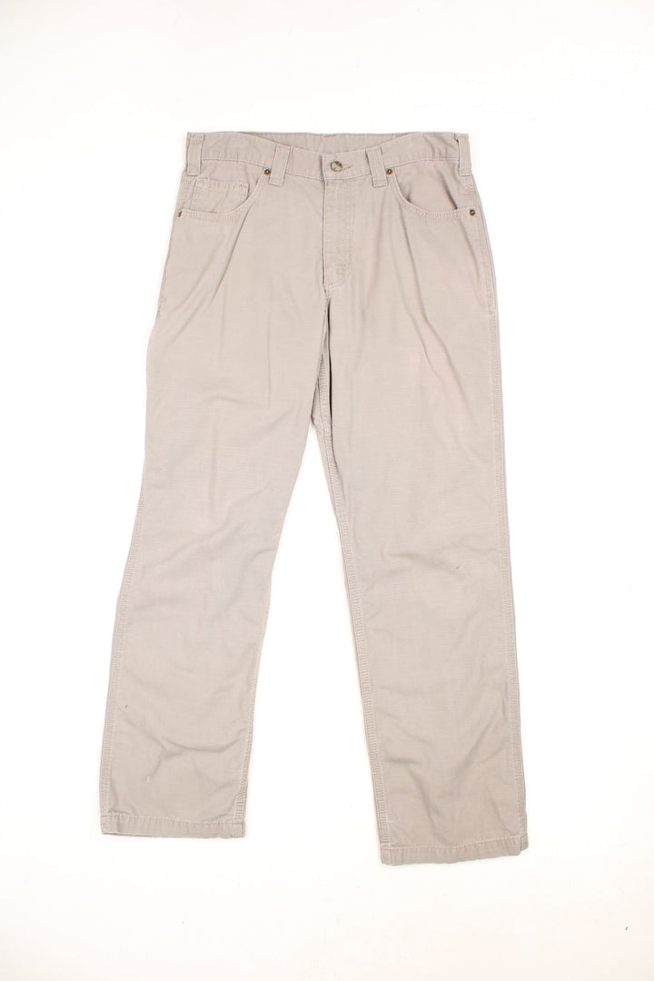 Carhartt grey-beige trousers with front, back and side pockets and a logo patch on the back pocket. 