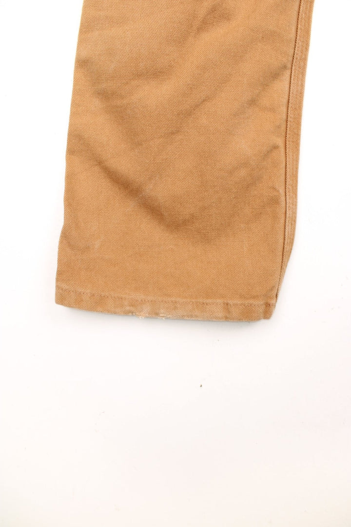 Carhartt tan carpenter jeans with a hammer loop, front, back and side pockets and a logo patch on the back pocket. 