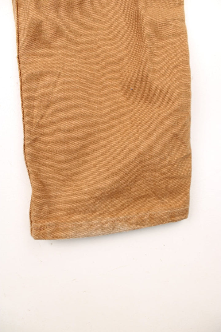 Carhartt tan carpenter jeans with a hammer loop, front, back and side pockets and a logo patch on the back pocket. 