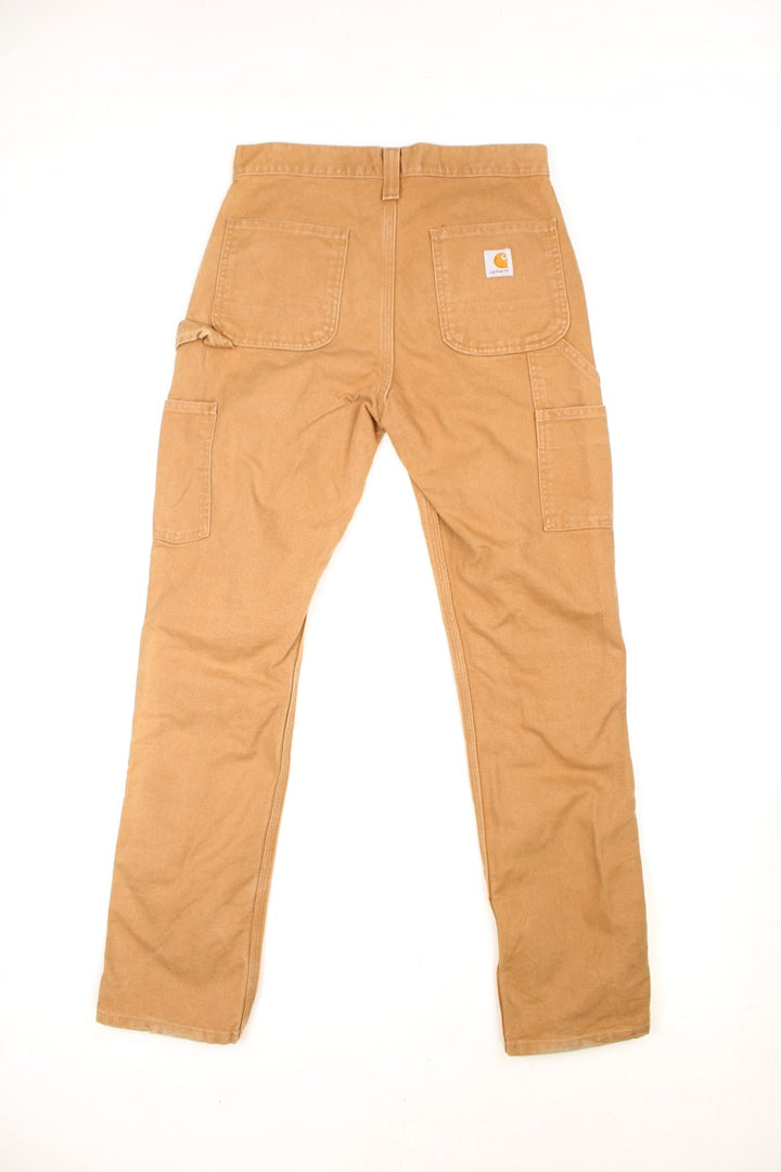 Carhartt tan carpenter jeans with a hammer loop, front, back and side pockets and a logo patch on the back pocket. 