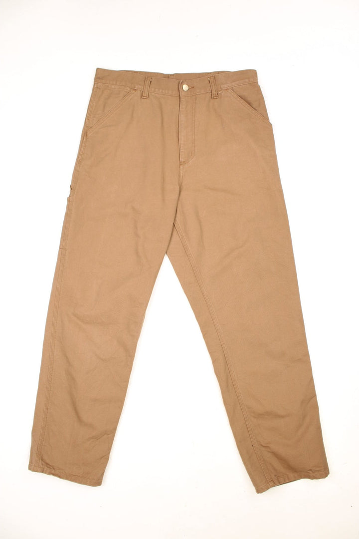 Carhartt tan carpenter jeans with a hammer loop, front, back and side pockets and a logo patch on the back pocket. 