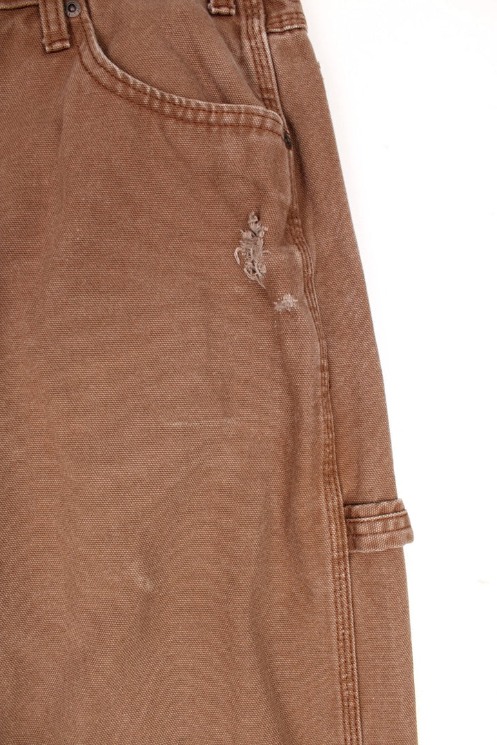 Dickies tan carpenter jeans with a hammer loop, front, back and side pockets and a logo patch on the back pocket. 