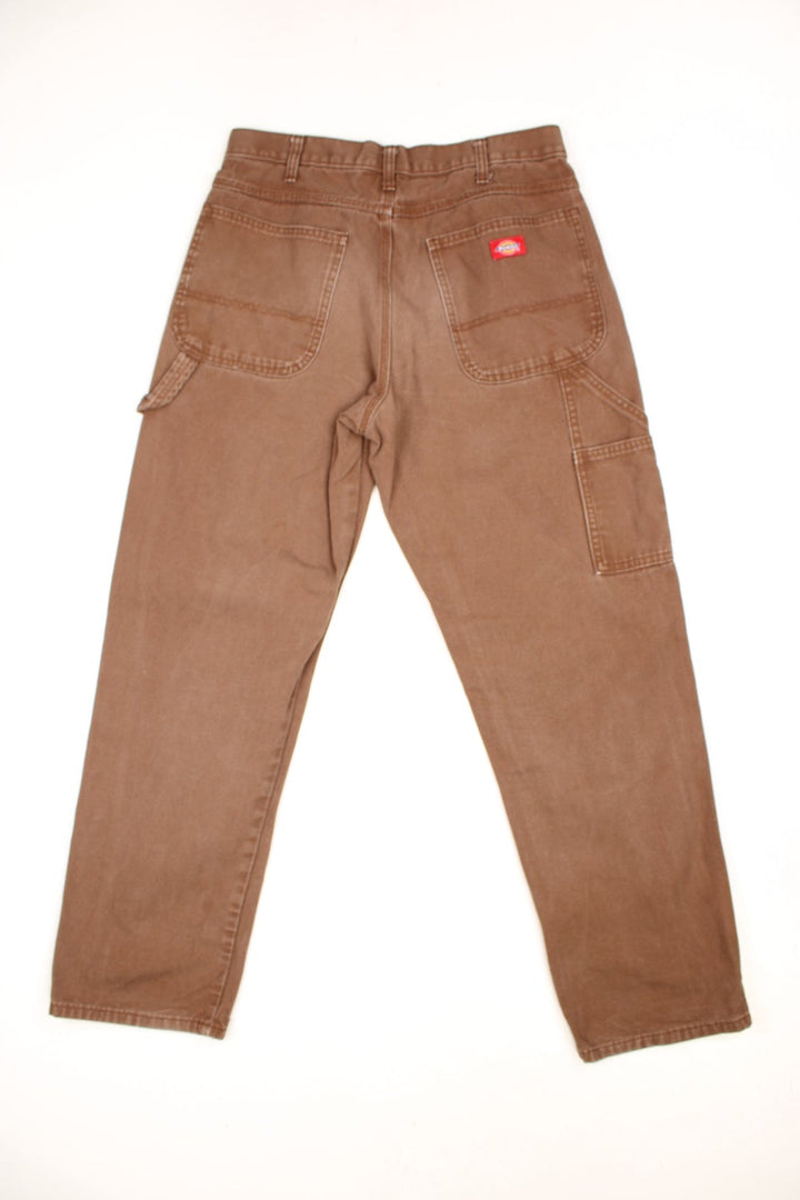 Dickies tan carpenter jeans with a hammer loop, front, back and side pockets and a logo patch on the back pocket. 