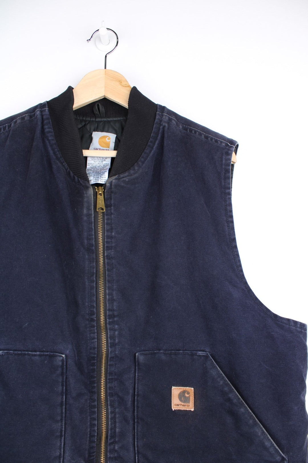 Carhartt Gilet Jacket in an indigo blue colourway. The gilet has two front pockets, a metal zippper to close, and the Carhartt leather patch stitched onto the pocket. 