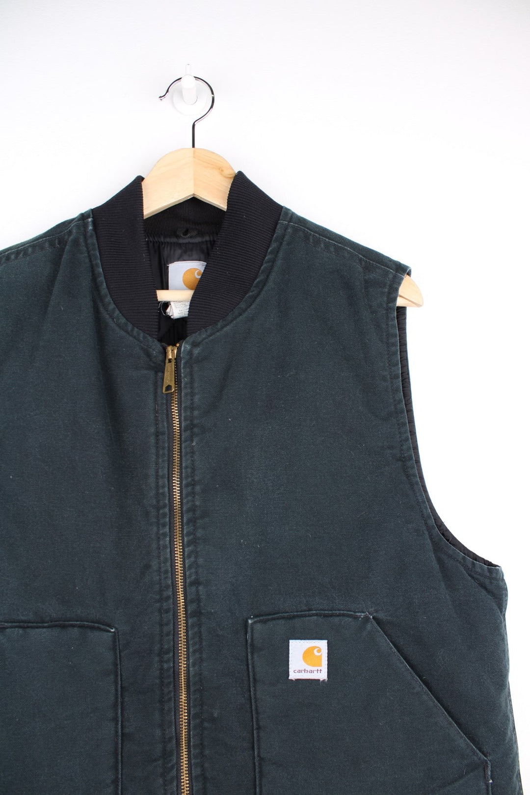 Carhartt Gilet Jacket in a dark green colourway. The gilet has two front pockets, a metal zip to close and the Carhartt logo stitched onto the front.  