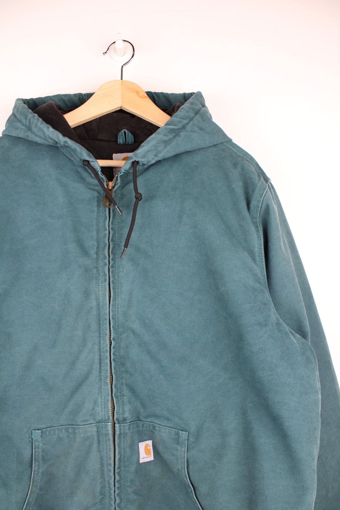  Carhartt Active Hooded Jacket in a teal green colourway. The jacket has two front pockets, a hood and an elasticated cuff on the sleeves and hem.