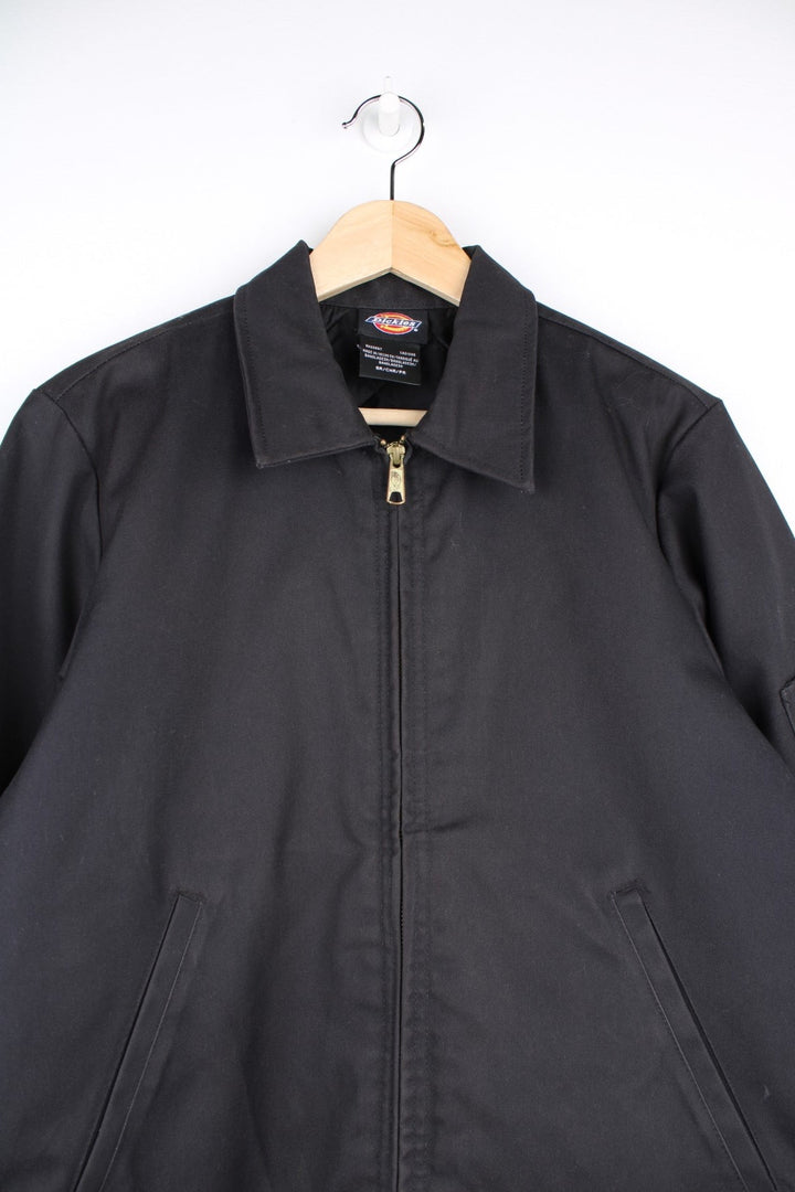 Dickies Workwear Jacket in a black colourway. The jacket two jetted pockets on the front, a silver zip to close and a small patch pocket on the left sleeve. 