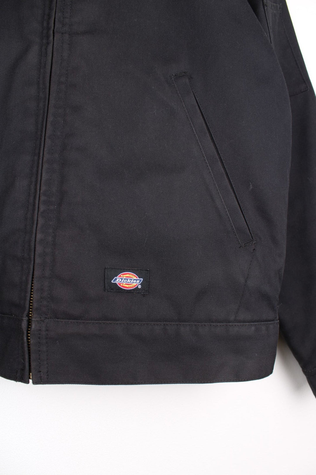 Dickies Workwear Jacket in a black colourway. The jacket two jetted pockets on the front, a silver zip to close and a small patch pocket on the left sleeve. 