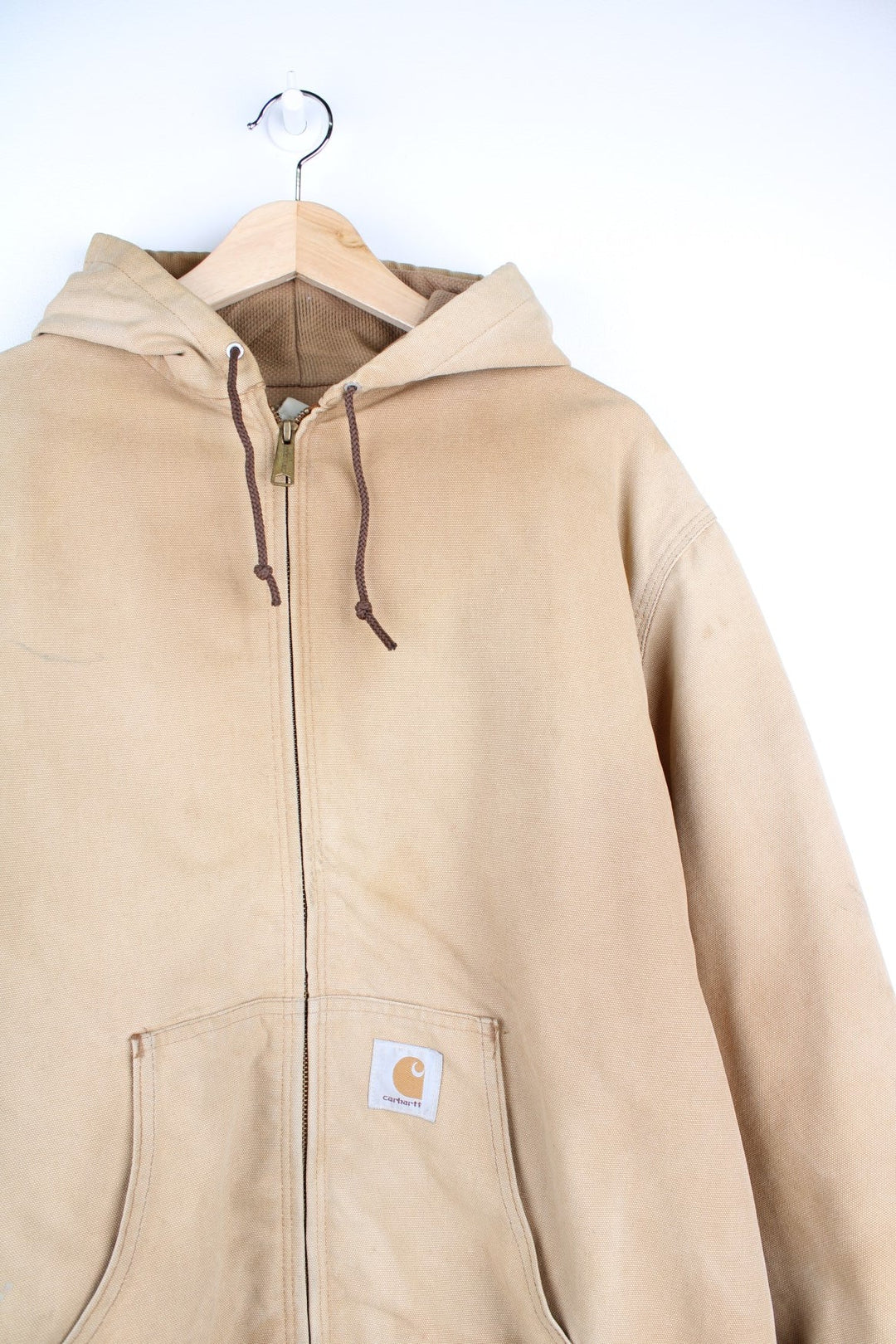 Vintage Carhartt Active Hooded Jacket in a tan colourway. The jacket has two front pockets, a gold zip to close and the Carhartt logo stitched onto the front. 