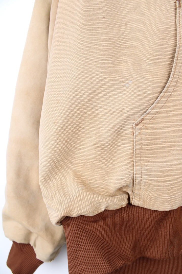 Vintage Carhartt Active Hooded Jacket in a tan colourway. The jacket has two front pockets, a gold zip to close and the Carhartt logo stitched onto the front. 