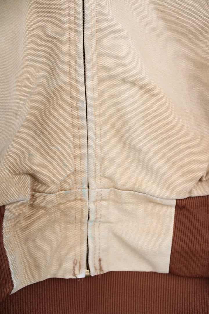 Vintage Carhartt Active Hooded Jacket in a tan colourway. The jacket has two front pockets, a gold zip to close and the Carhartt logo stitched onto the front. 