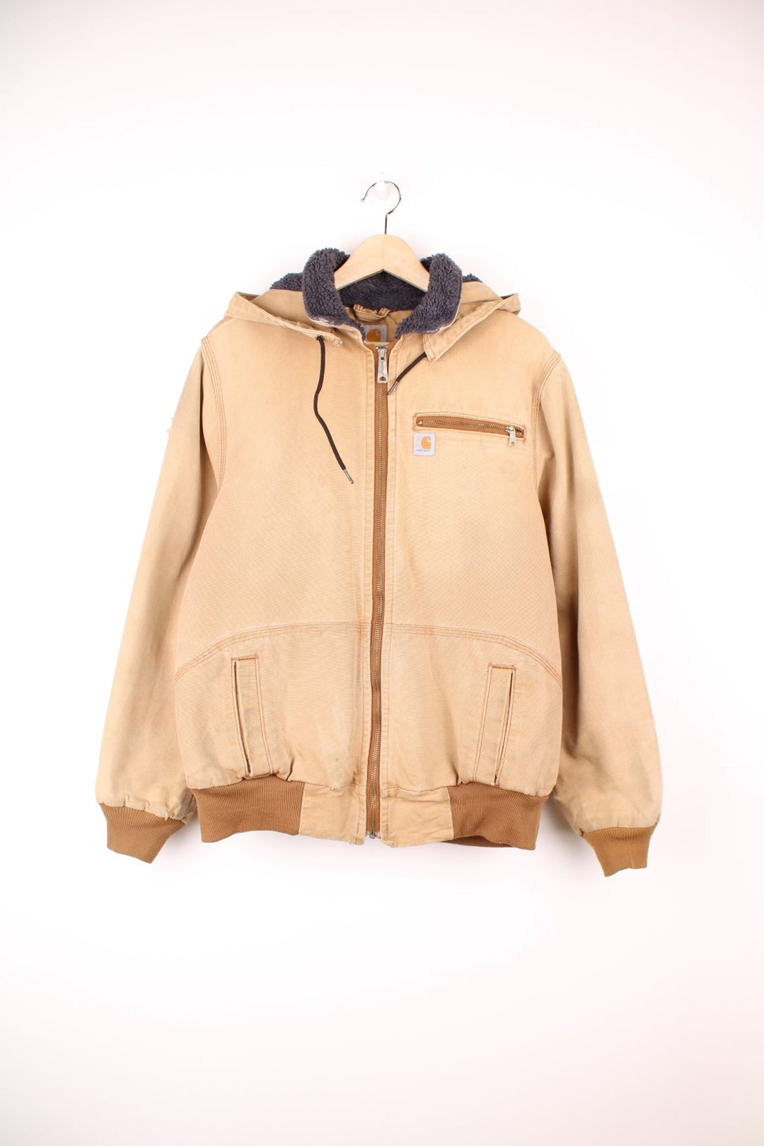 Carhartt Wildwood Sherpa Jacket in tan with zip closure, multiple pockets, sherpa lining, detachable hood and the logo embroidered on the front. 