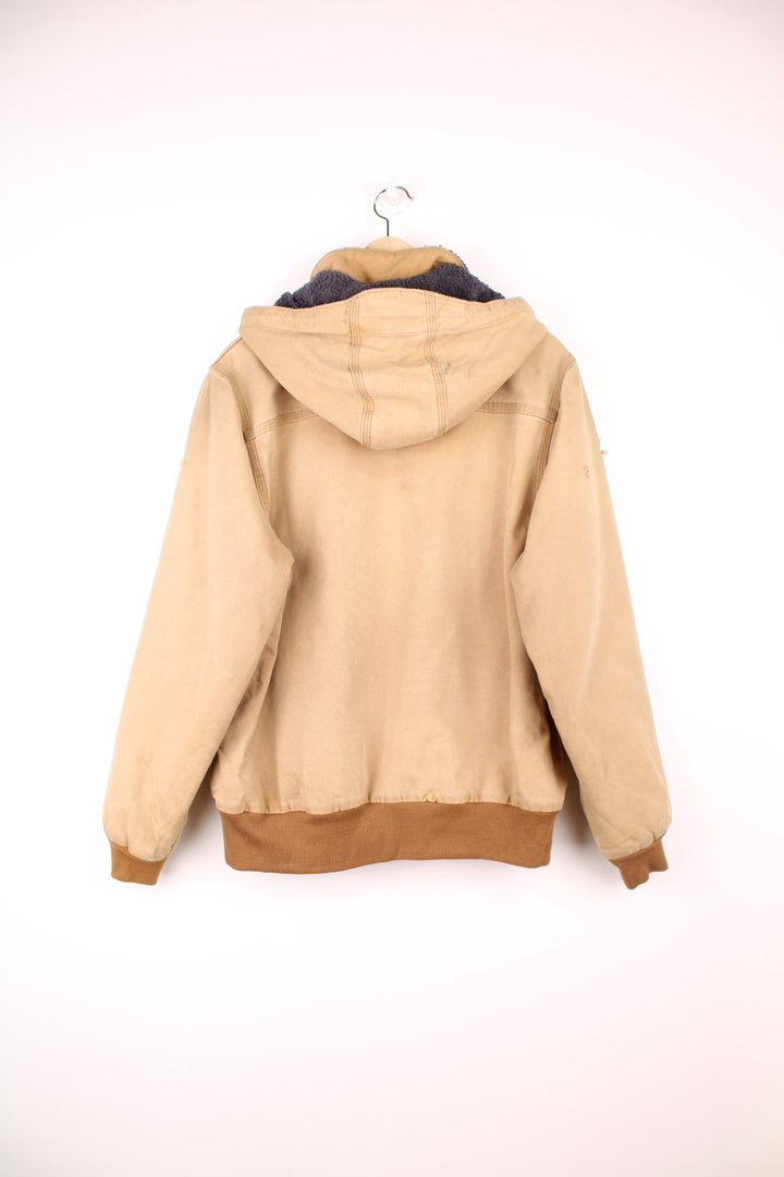 Carhartt Wildwood Sherpa Jacket in tan with zip closure, multiple pockets, sherpa lining, detachable hood and the logo embroidered on the front. 