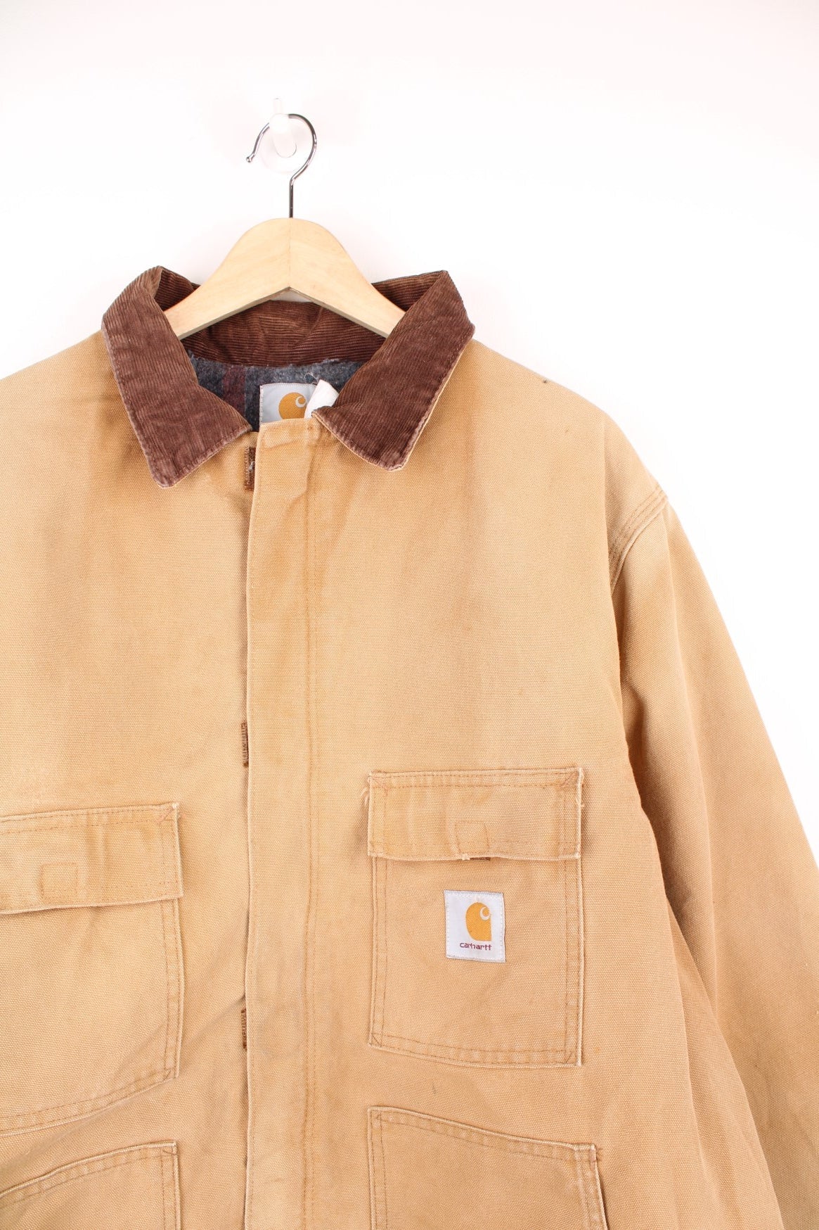 Carhartt Detroit jacket in tan. Blanket lined with a brown corduroy collar, zip and velcro closure, four pockets with a logo patch on the upper left. 