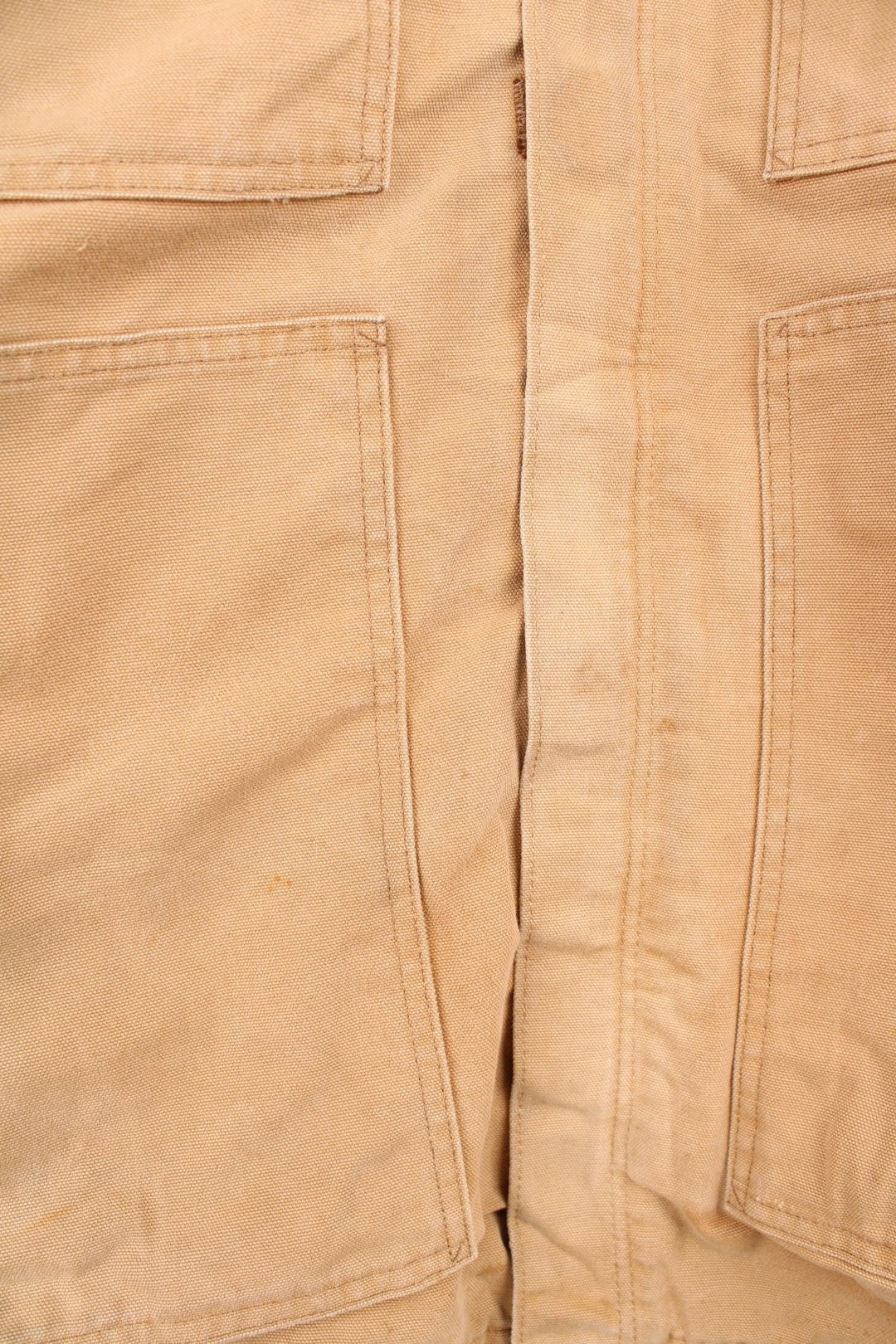 Carhartt Detroit jacket in tan. Blanket lined with a brown corduroy collar, zip and velcro closure, four pockets with a logo patch on the upper left. 