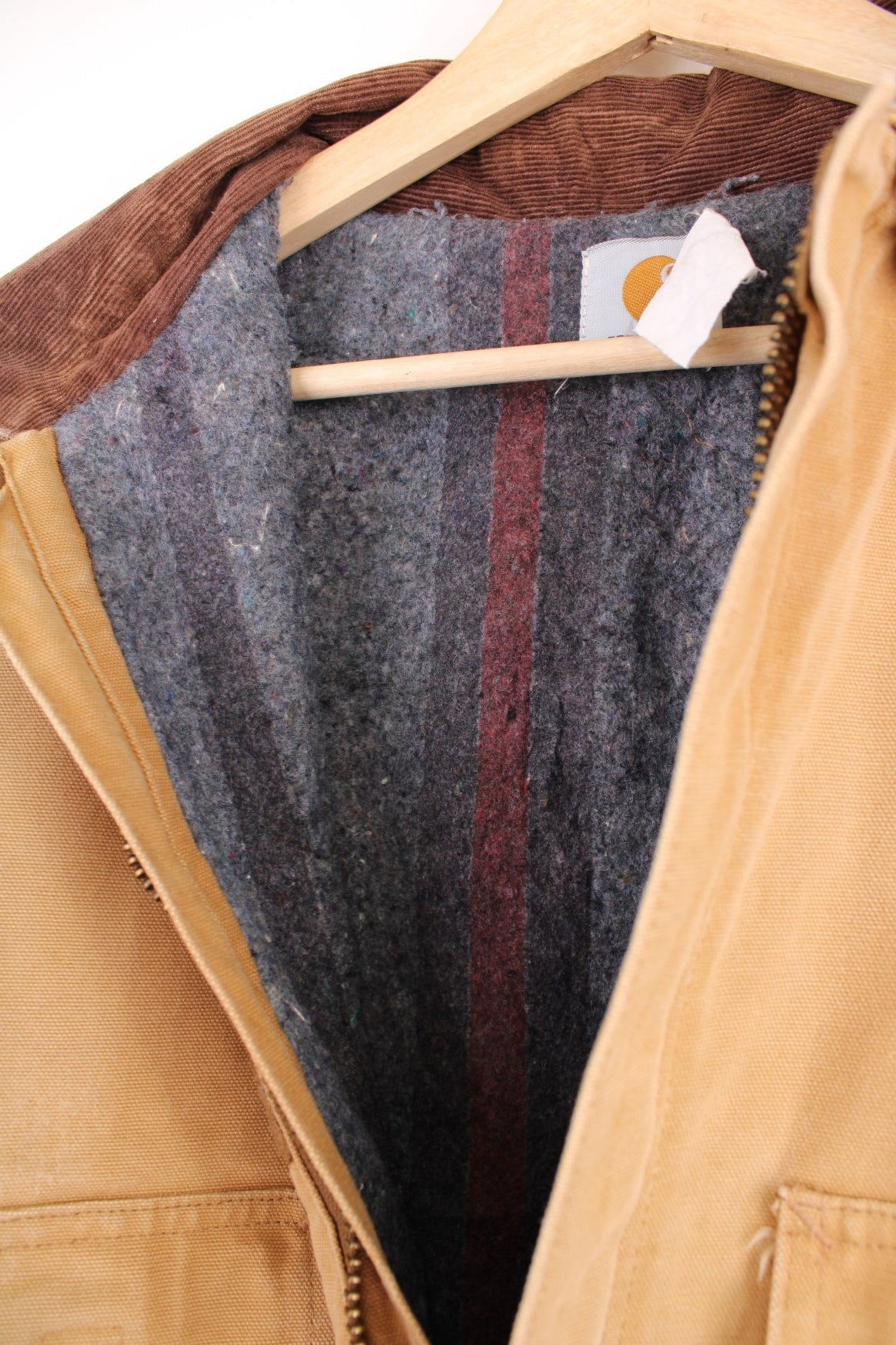 Carhartt Detroit jacket in tan. Blanket lined with a brown corduroy collar, zip and velcro closure, four pockets with a logo patch on the upper left. 