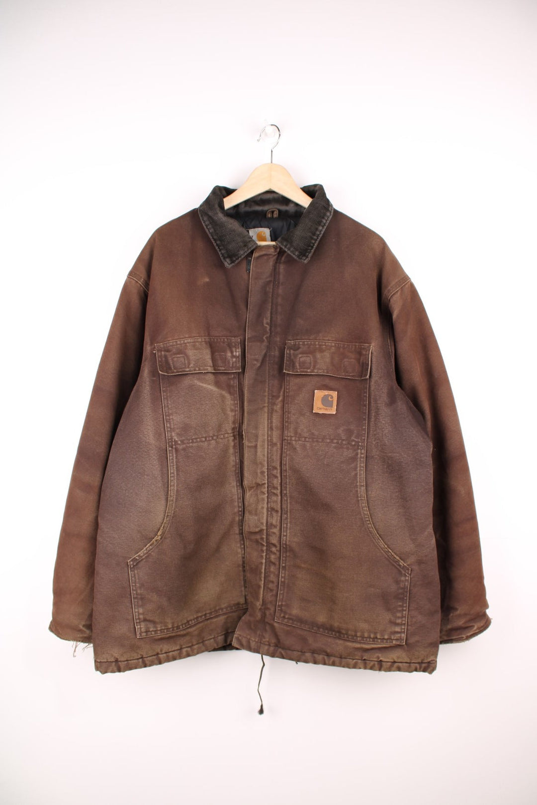 Carhartt Arctic jacket in brown. Quilt lined, with a dark brown corduroy collar,zip and velcro closure, four pockets and a leather logo patch on the upper left.  