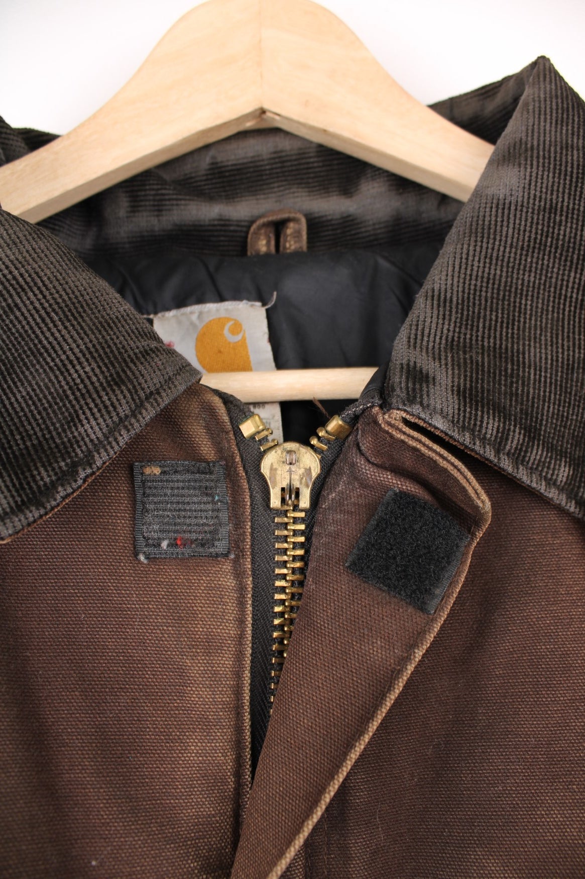 Carhartt Arctic jacket in brown. Quilt lined, with a dark brown corduroy collar,zip and velcro closure, four pockets and a leather logo patch on the upper left.  