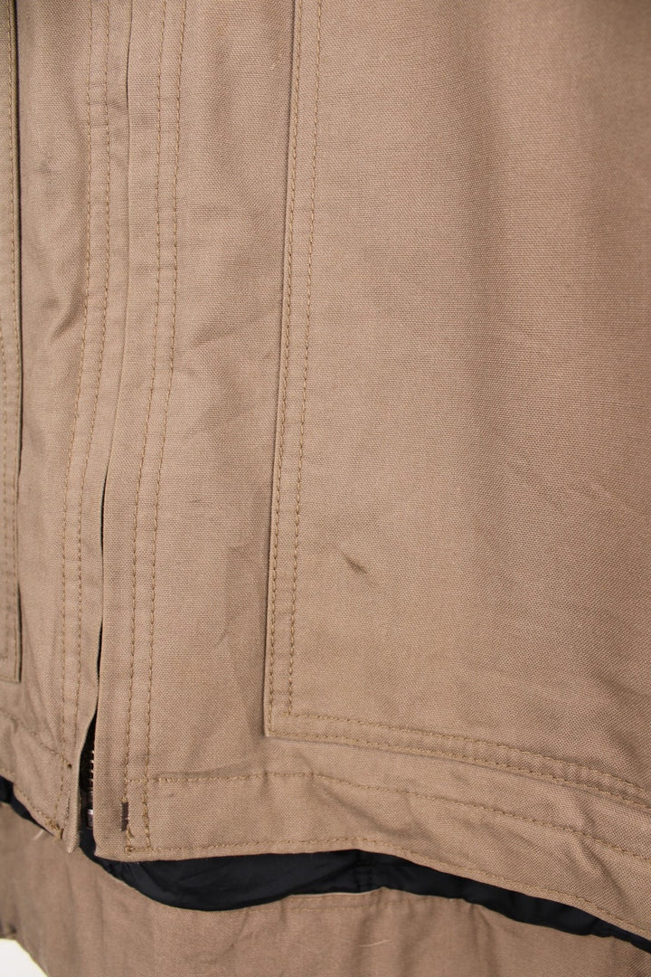 Carhartt work jacket in tan with four pockets, zip closure, a Carhartt logo patch on the upper left and a 'QD Quick Duck' logo on the left sleeve. 