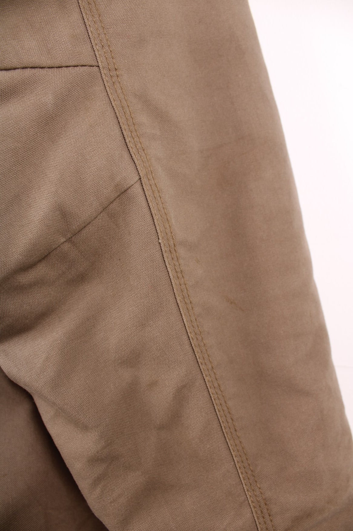 Carhartt work jacket in tan with four pockets, zip closure, a Carhartt logo patch on the upper left and a &