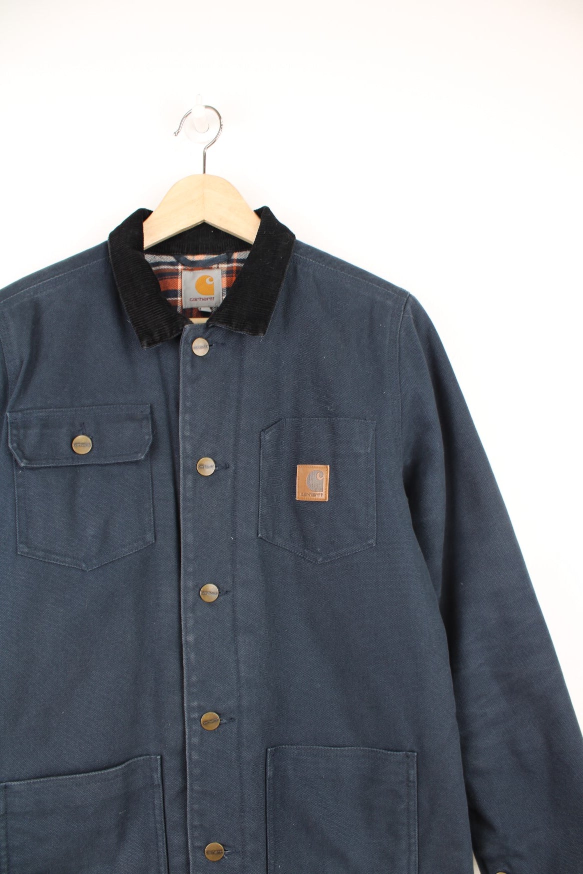 Carhartt Workwear Jacket in a blue colourway with a black corduroy collar, button up with multiple pockets and has the logo embroidered on the front. 