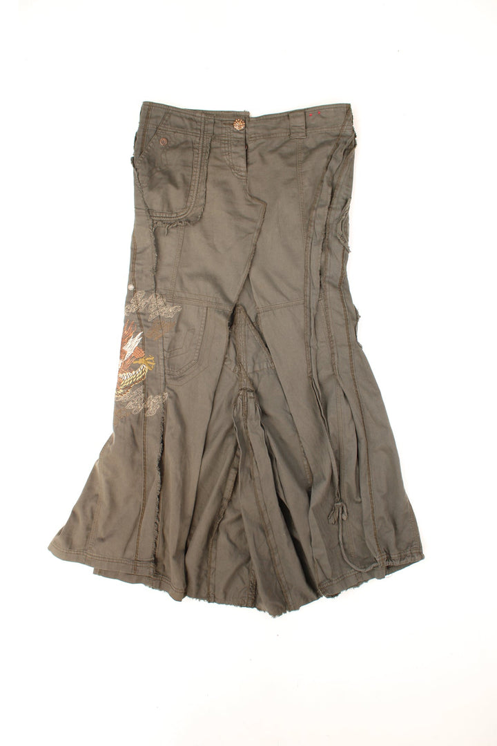 Y2K distressed embroidered maxi skirt by River Island with asymettrically placed pockets, pleats and a central slit in the front, with embellished button closure. 