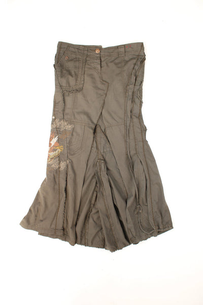 Y2K distressed embroidered maxi skirt by River Island with asymettrically placed pockets, pleats and a central slit in the front, with embellished button closure. 