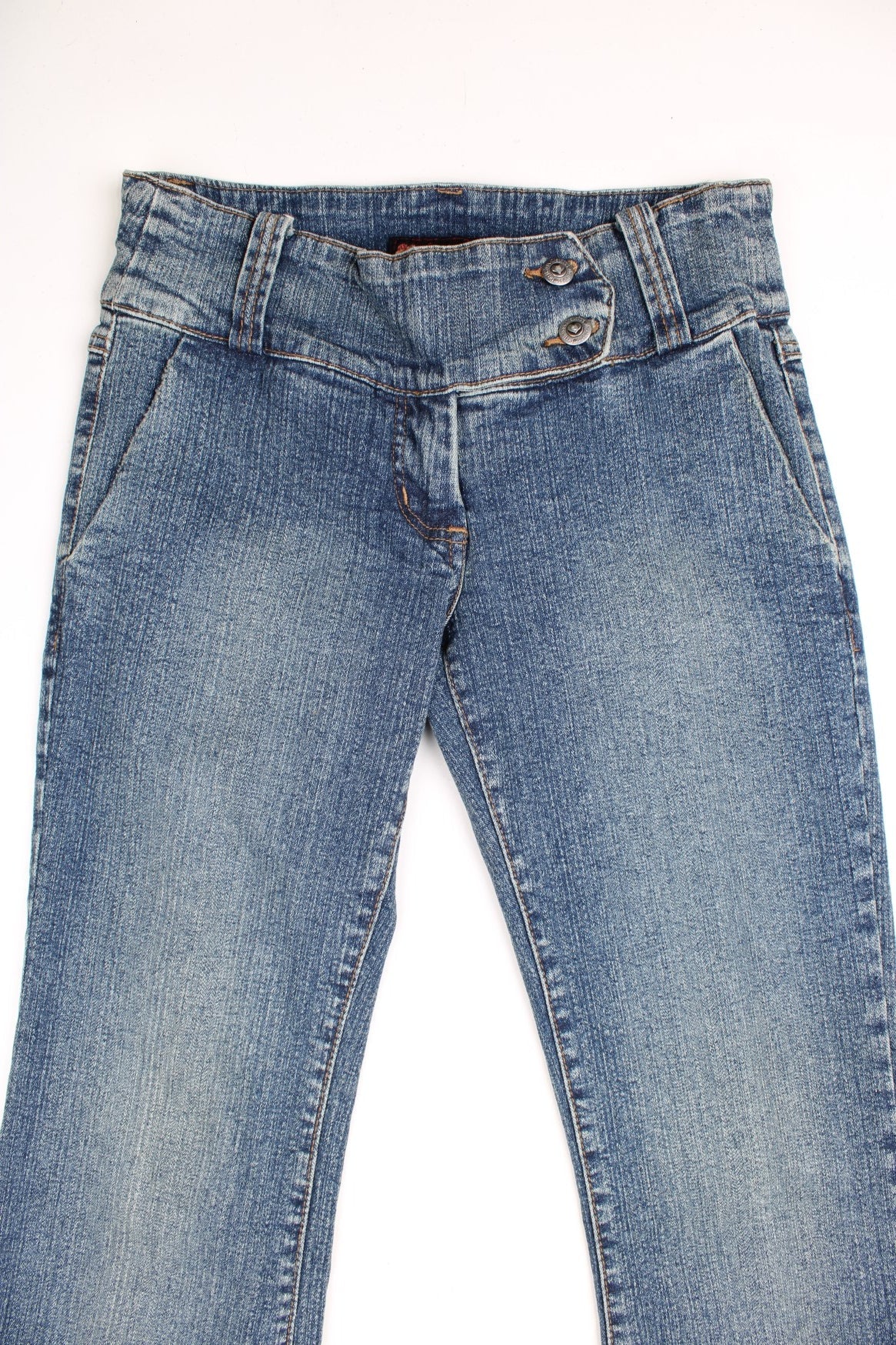 Y2K low rise bootcut jeans with four pockets and a buttoned belt detail.