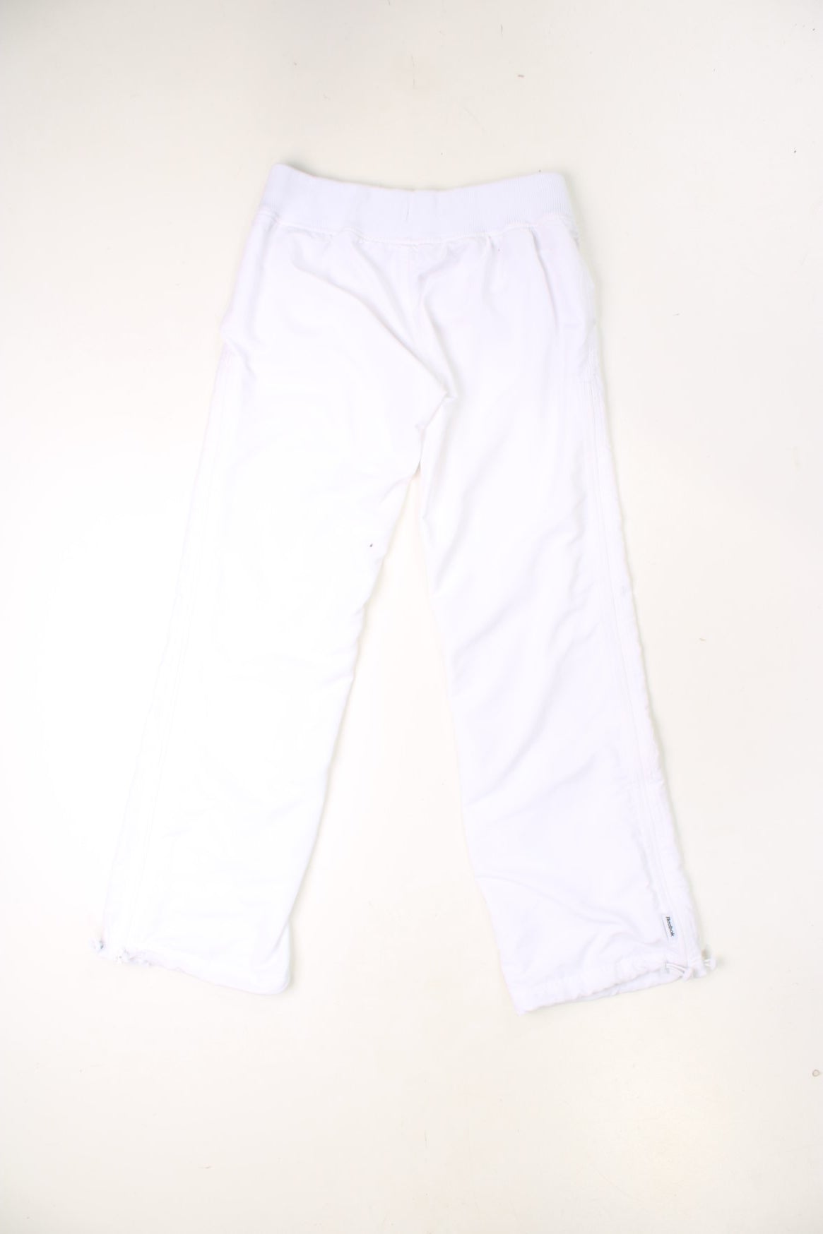 Vintage Reebok trousers with elasticated waistband and drawstring. Features embroidered logo, zips up each leg and toggle pulls on each cuff. 