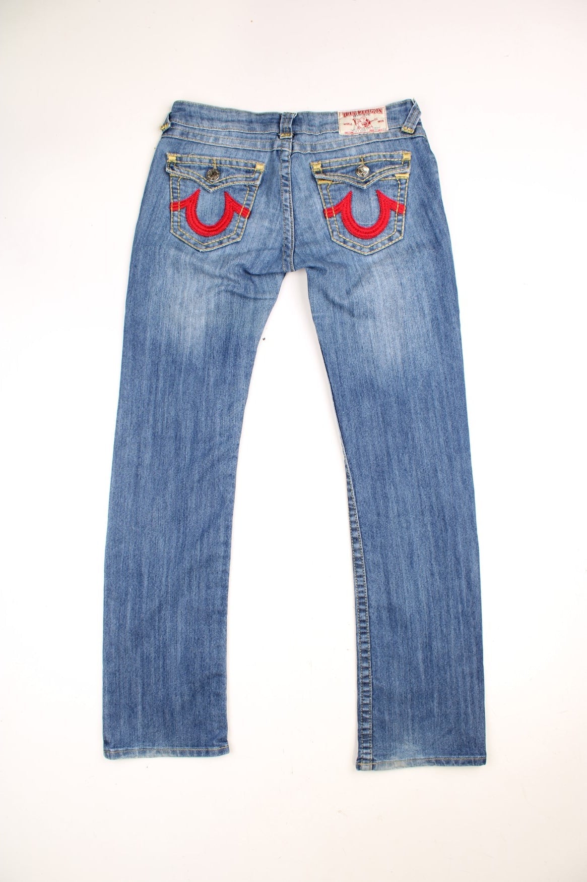 True Religion low rise straight leg jeans in a faded blue wash. Signature horseshoe embroidery in red on back pockets.  