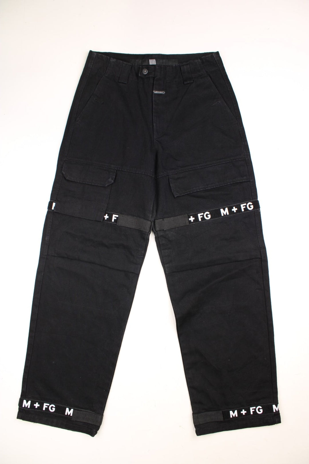 Marithe Francios Girbuad Y2K Trousers in a black colourway with multiple utility style pockets, velcros straps going down the legs with 'M + FG' embroidered on. 