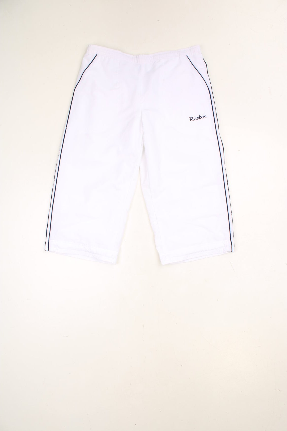 White Reebok Capri Shorts with elasticated, drawstring waist and embroidered spell out logo in blue.