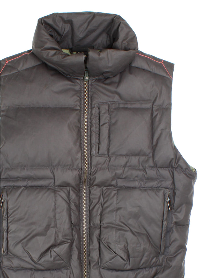 Diesel puffer gilet in brown with three pockets, a branded patch on the back, orange contrast stitching, and zip closure.