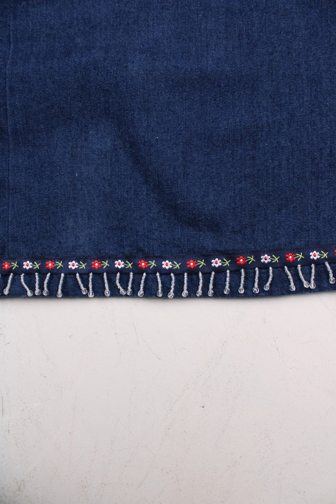 Vintage Denim Skirt in blue colourway with floral bead patterns embroidered on the hem, high waisted and has side pockets.