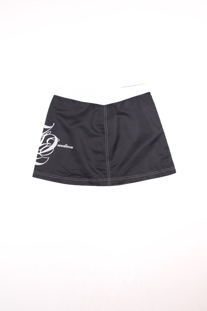 Y2K Nike Sporting Excellence Mini Skirt in black and white colourway with the logo and graphic spell out printed around the left side.